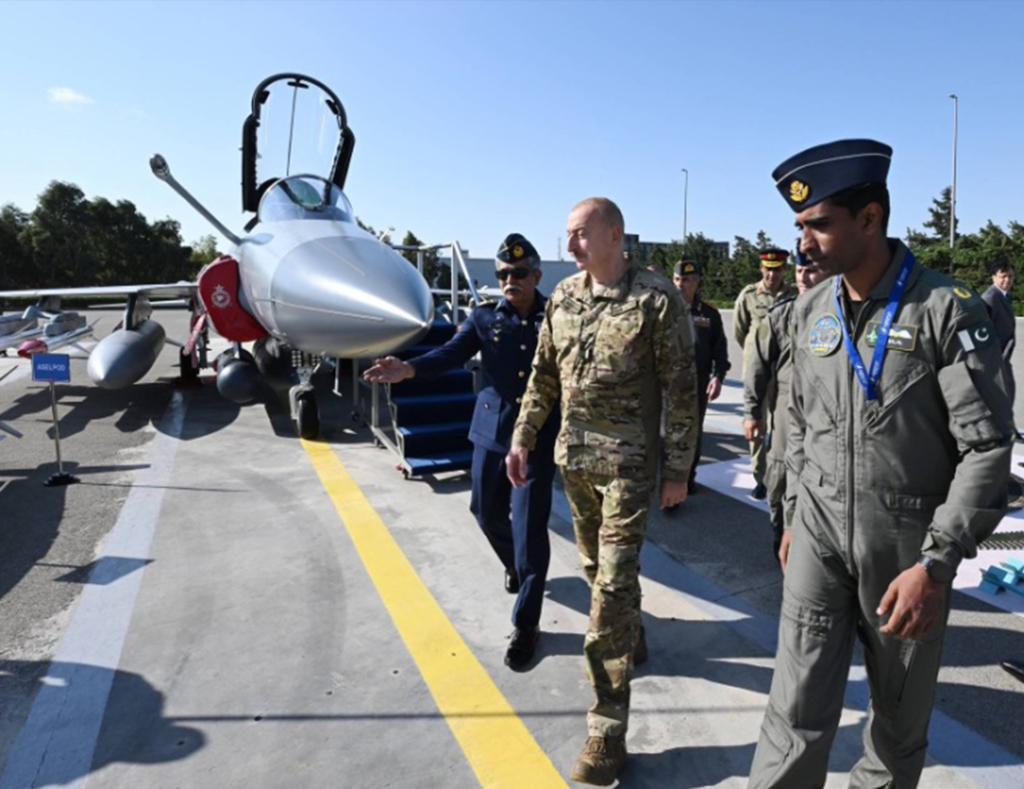 Ilham Aliyev standing in front of a JF-17 Block-III fighter jet during a defense-related event.